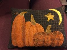 a knitted pumpkin pillow sitting on top of a purple couch