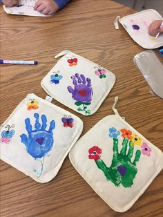 three children's handprinted pot holders on a table