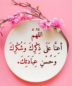 a plate with some pink flowers on it and an arabic quote written in two languages