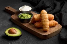 croissants and avocado on a cutting board with dip in a bowl