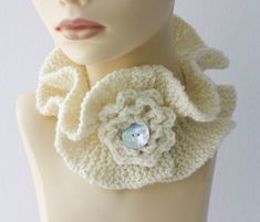 a mannequin head wearing a white crocheted scarf with a flower on it