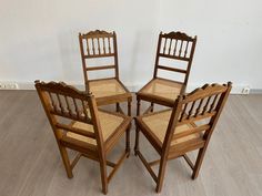 four wooden chairs sitting next to each other on top of a hard wood floored floor