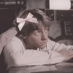 a man with a bow on his head sitting at a table in front of a laptop