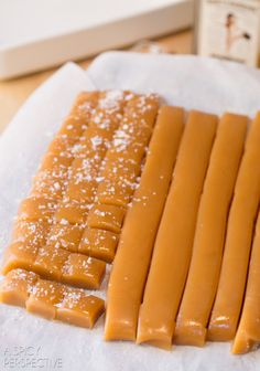 several pieces of caramel on top of wax paper next to a bottle of wine