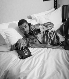 a man laying on top of a bed next to a calculator and cell phone