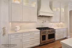 a kitchen with white cabinets and stainless steel stove top oven in the center of the room