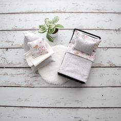 a white table topped with lots of pillows next to a small potted plant on top of a wooden floor