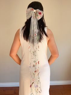 a woman wearing a veil with flowers on it and a bow in her hair is looking at the wall