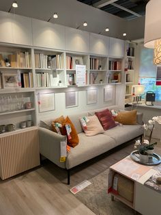 a living room filled with lots of furniture and bookshelves next to a window