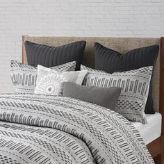 a bed with black and white comforter on top of it next to a brick wall