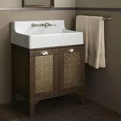 a white sink sitting under a bathroom mirror next to a wooden cabinet and towel rack