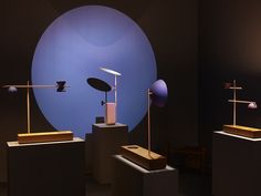 three different types of lamps on pedestals in front of a blue circle