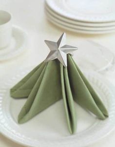 folded napkins with silver stars on them sitting on a white dinner table set for two