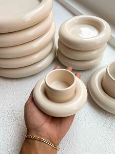 a hand holding a stack of white dishes