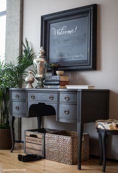 a black desk with baskets underneath it and a chalkboard on the wall