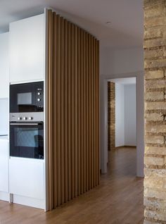 a kitchen with white cabinets and wooden slats on the wall, along with an oven