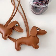 a pair of brown leather dachshund key fobs sitting on top of a table