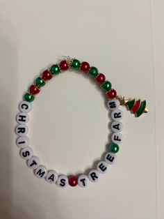 a beaded bracelet with the word merry written in white letters and green, red and gold beads