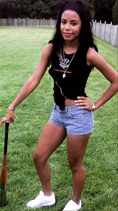 a woman standing in the grass holding a baseball bat