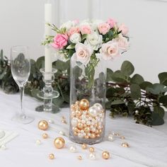 a vase filled with flowers and pearls on top of a table next to two wine glasses