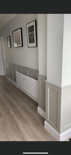 an empty room with white walls and wood flooring in the center, along with pictures on the wall