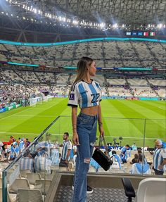 a woman is standing in the stands at a soccer game with her hand on her hip