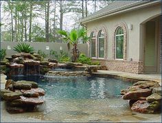 an outdoor pool with rocks and water features