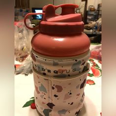 a red and white cup sitting on top of a table next to a plastic container