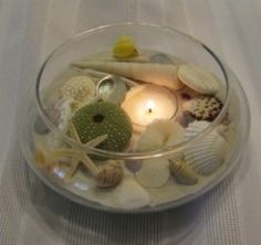 a glass bowl filled with shells and candles