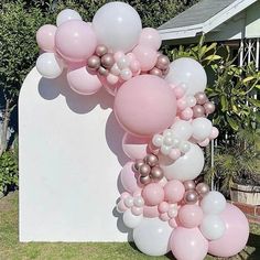 a bunch of balloons that are on the ground in front of a sign and some bushes