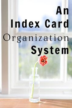 an index card organization system on a table with a flower in a vase next to it