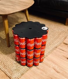 a stack of coca - cola cans sitting on top of a rug next to a table