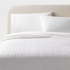 a bed with white sheets and pillows on it