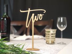 there is a table with two wine glasses and a sign on it that says two