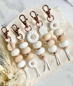 six pairs of wooden bead charms on a piece of cloth with flowers and feathers