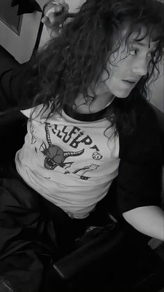 a woman sitting on the floor with her hair blowing in the wind and wearing a t - shirt that says hippop