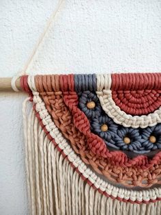 a close up of a wall hanging made out of yarn and wooden sticks with beads