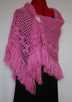 a pink crocheted shawl on a mannequin with a black dress underneath it