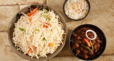 two bowls filled with rice and beans next to another bowl full of other food on a table