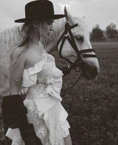 a woman in a dress and hat is standing next to a horse