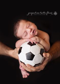 a baby sleeping on top of a white soccer ball in his father's hands