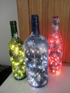 three bottles with lights in them sitting on a table