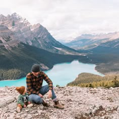 a man sitting on top of a rocky mountain next to a blue body of water