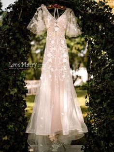 a wedding dress hanging in an archway with greenery