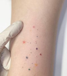 a person with a white glove on their arm holding up a small tattoo that has stars all over it