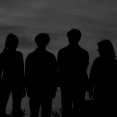 the silhouettes of three people against a cloudy sky