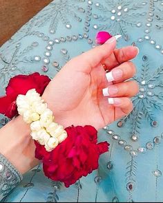 a woman's hand with white and red flowers on it