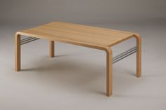 a wooden table sitting on top of a white floor next to a gray wall in an empty room