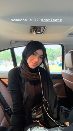 a young woman sitting in the back seat of a car listening to music on headphones