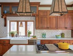 a kitchen with wooden cabinets and white counter tops, two pendant lights over the stove